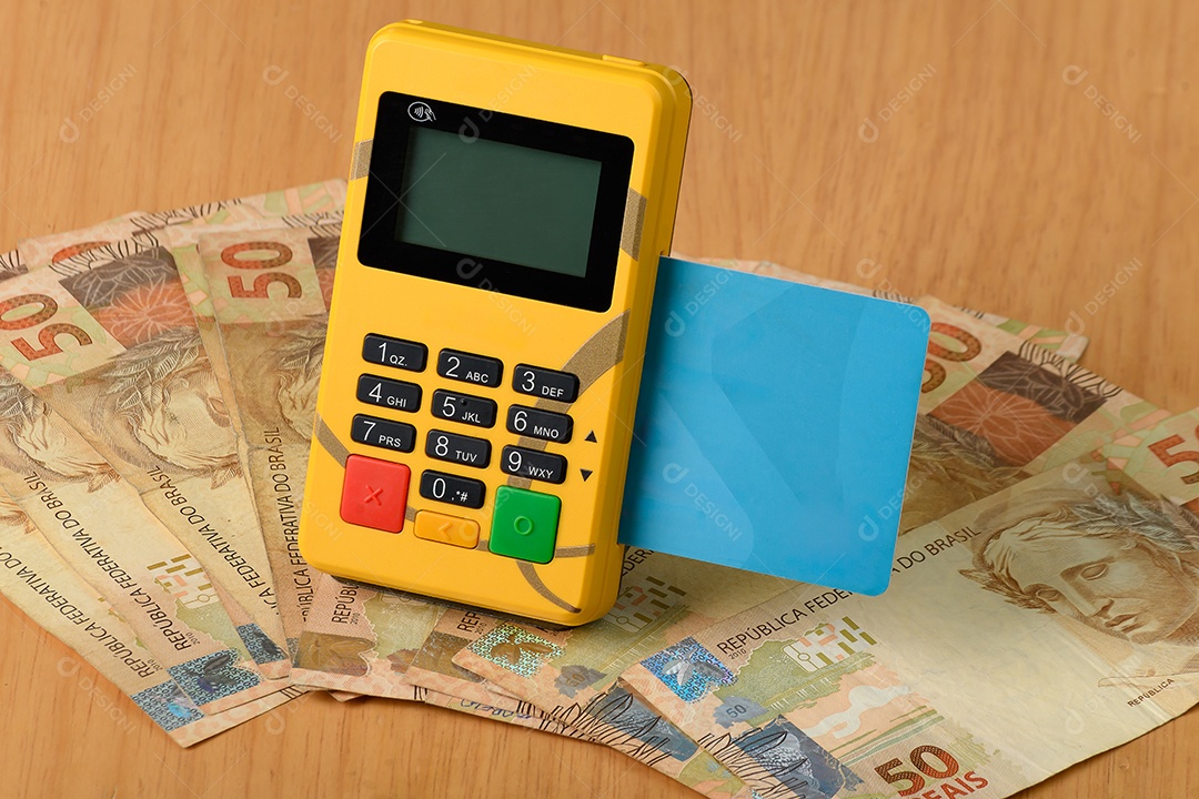 Notas de cinquenta reais e máquina de cartão sobre fundo de madeira