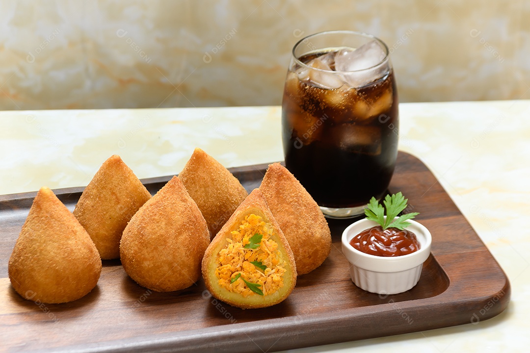 Tábua com coxinhas e molho de ketchup com copo de coca cola