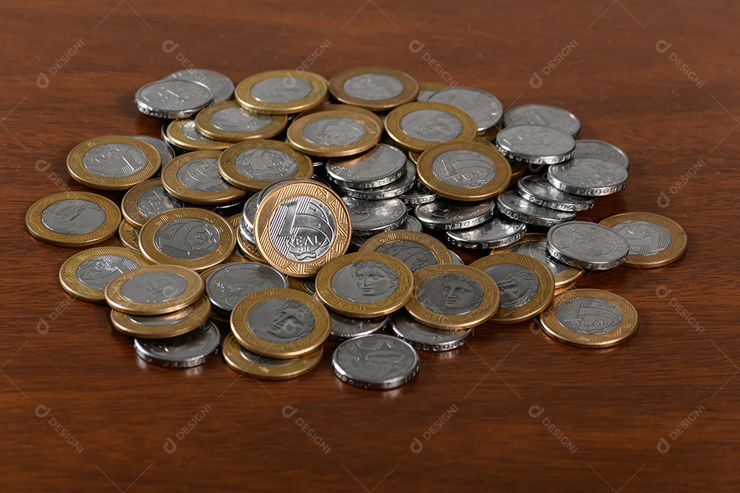 Muitas moedas de cinquenta e um real sobre mesa de madeira