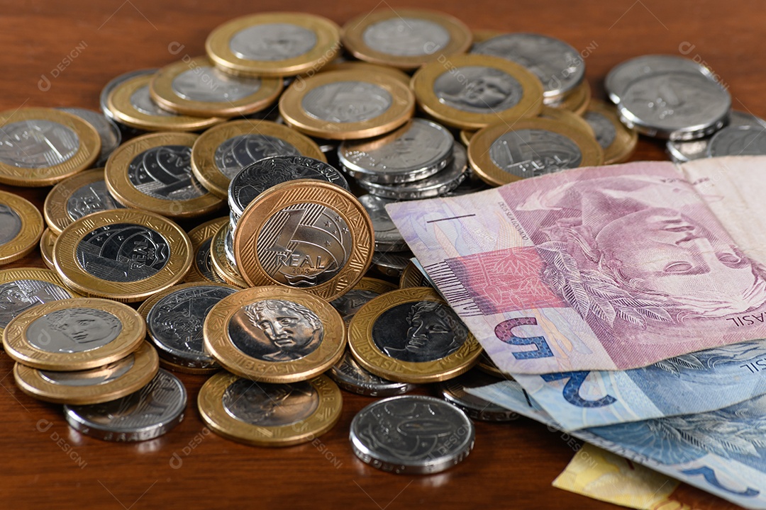 Muitas moedas e notas de dinheiro sobre uma mesa de madeira