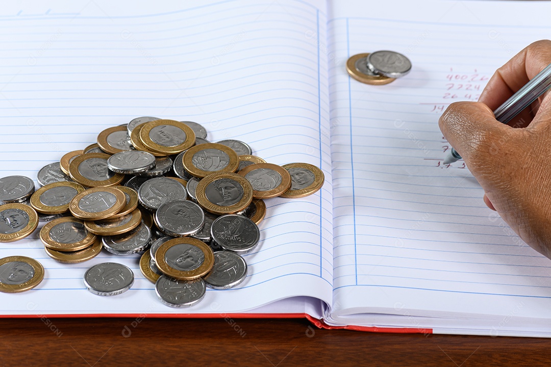 Moedas economia mão escrevendo em um caderno