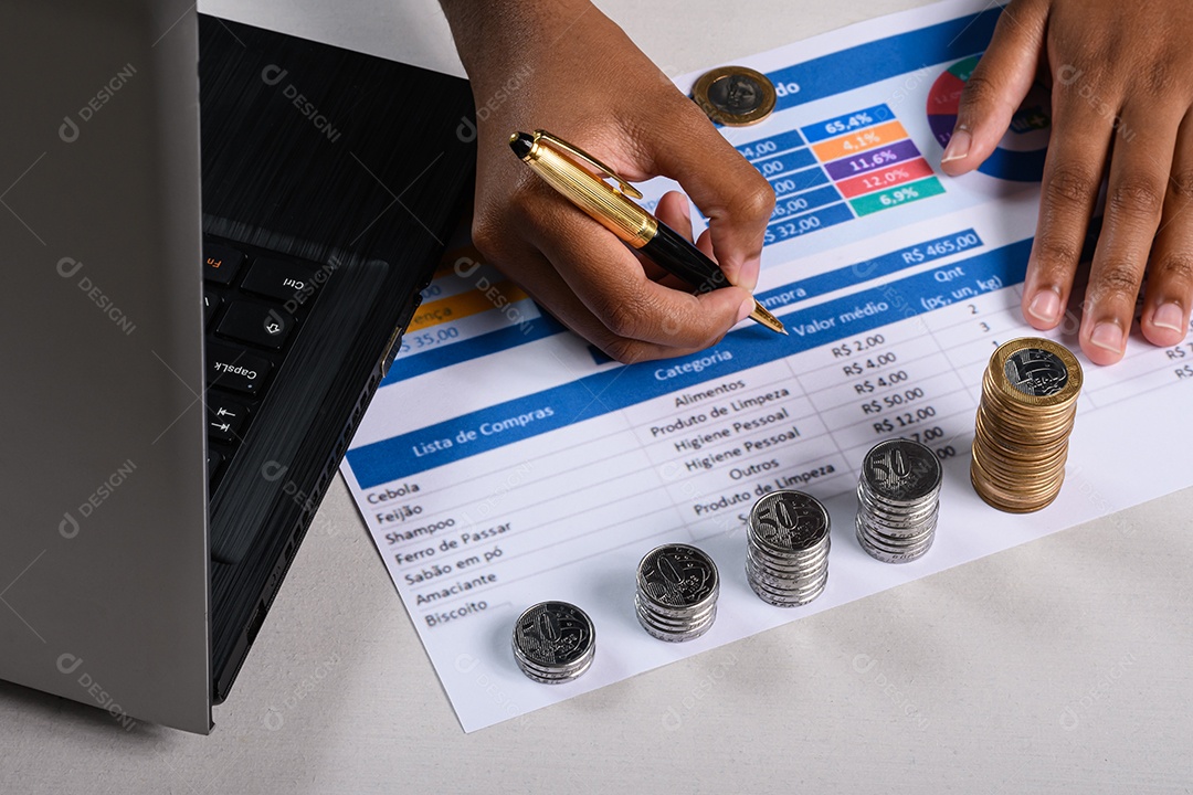 Mão no laptop analisando tabela pelo valor do real