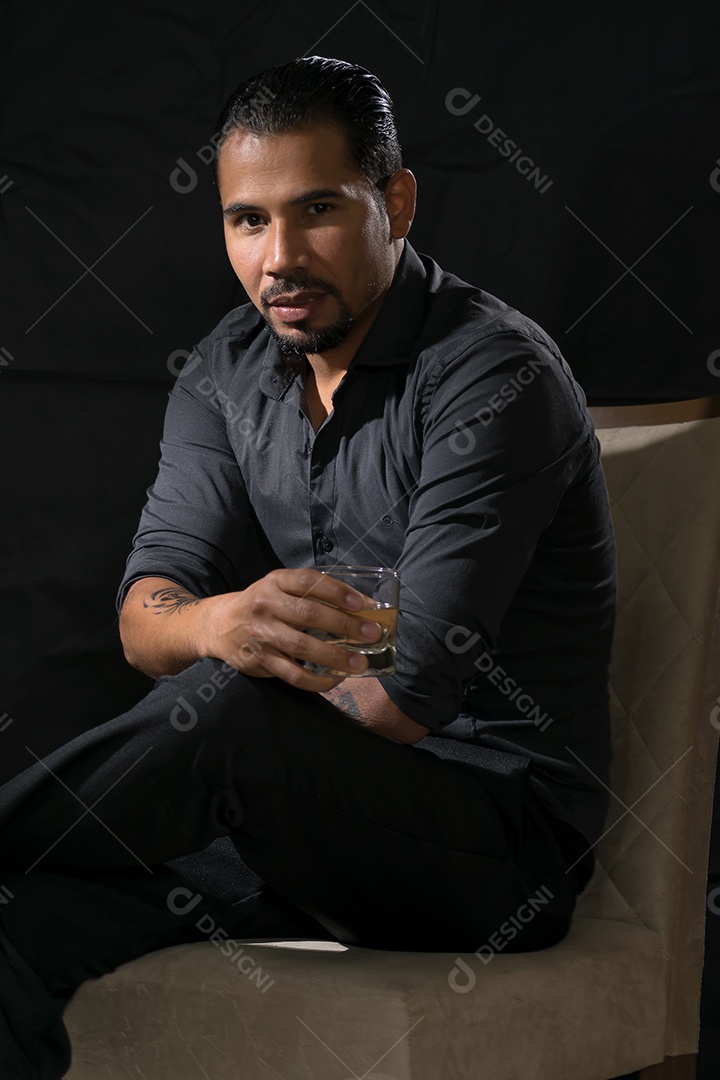 Um lindo homem sentando e moderno tomando whisky