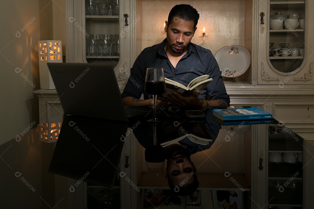 A beautiful businessman taking wine and reading a book