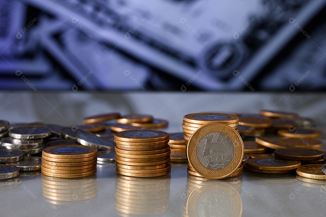 Moedas de um real empilhadas sobre uma mesa