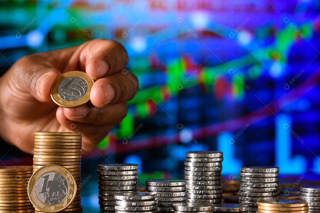 Mão empilhando moedas sobre fundo de um gráfico