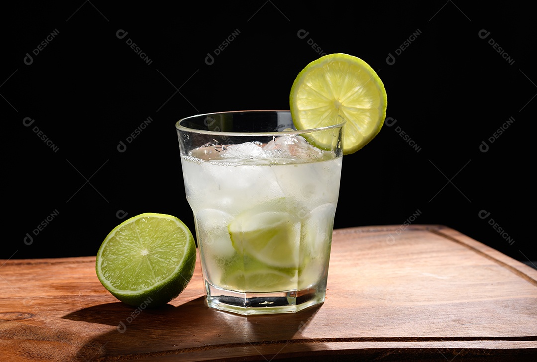 Um copo de caipirinha com limões