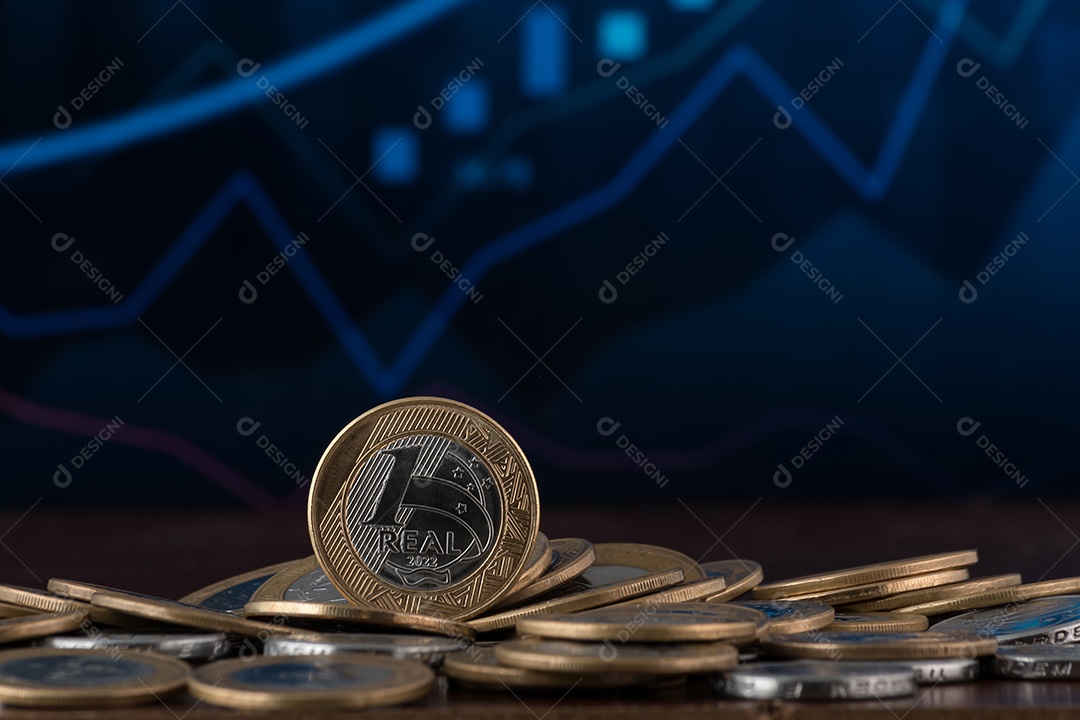 Várias moedas de um real sobre fundo de um gráfico