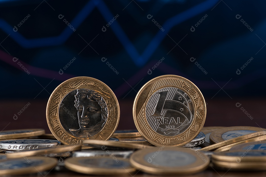 Muitas moedas de um real sobre uma mesa de madeira