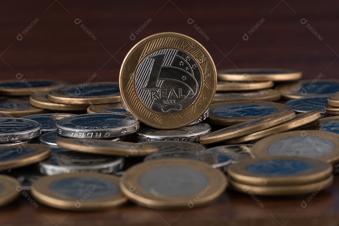Moedas de um real e cinquentas centavos sobre uma mesa de madeira