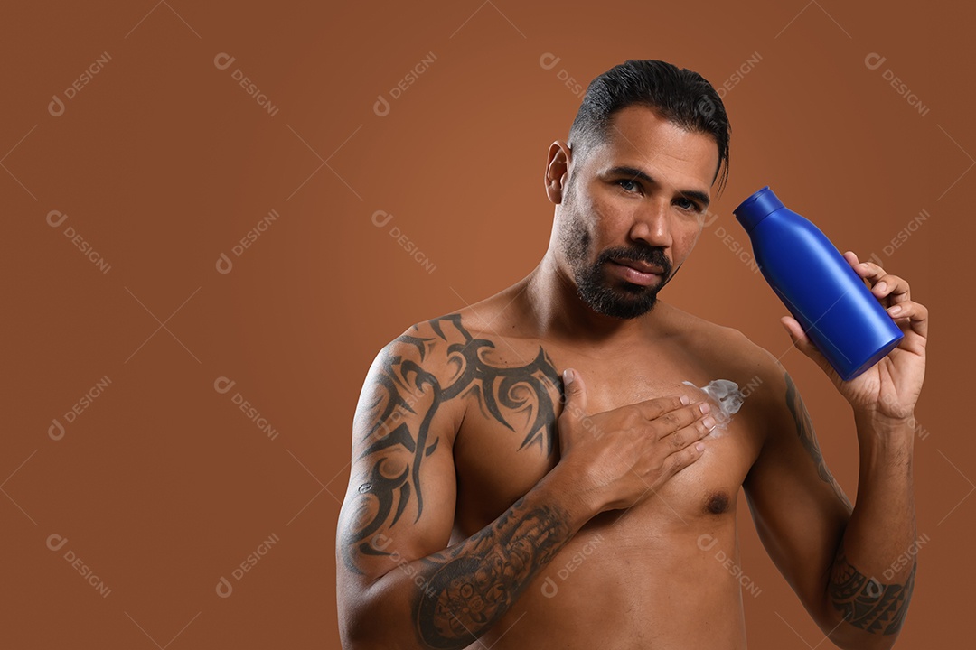 Homem tatuado sexy passando hidrante no corpo