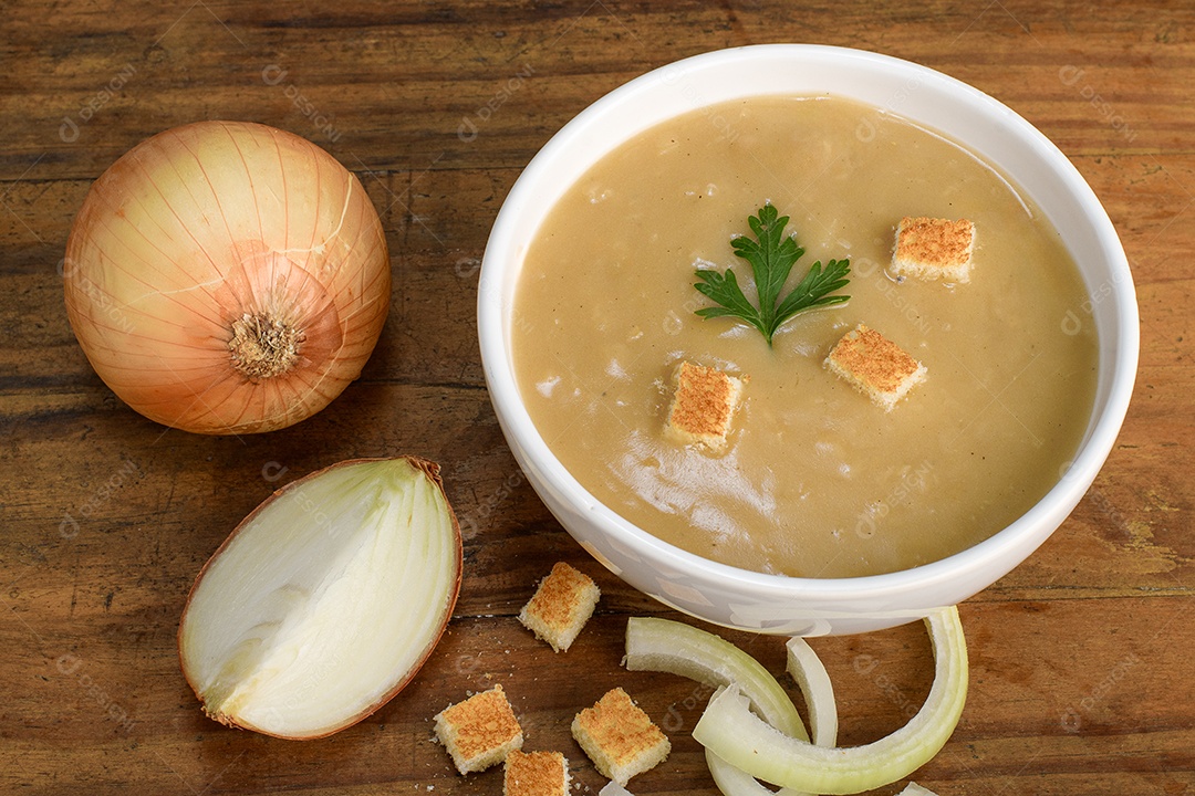 Sopa em uma tigela com pão frito e cebolas ao lado