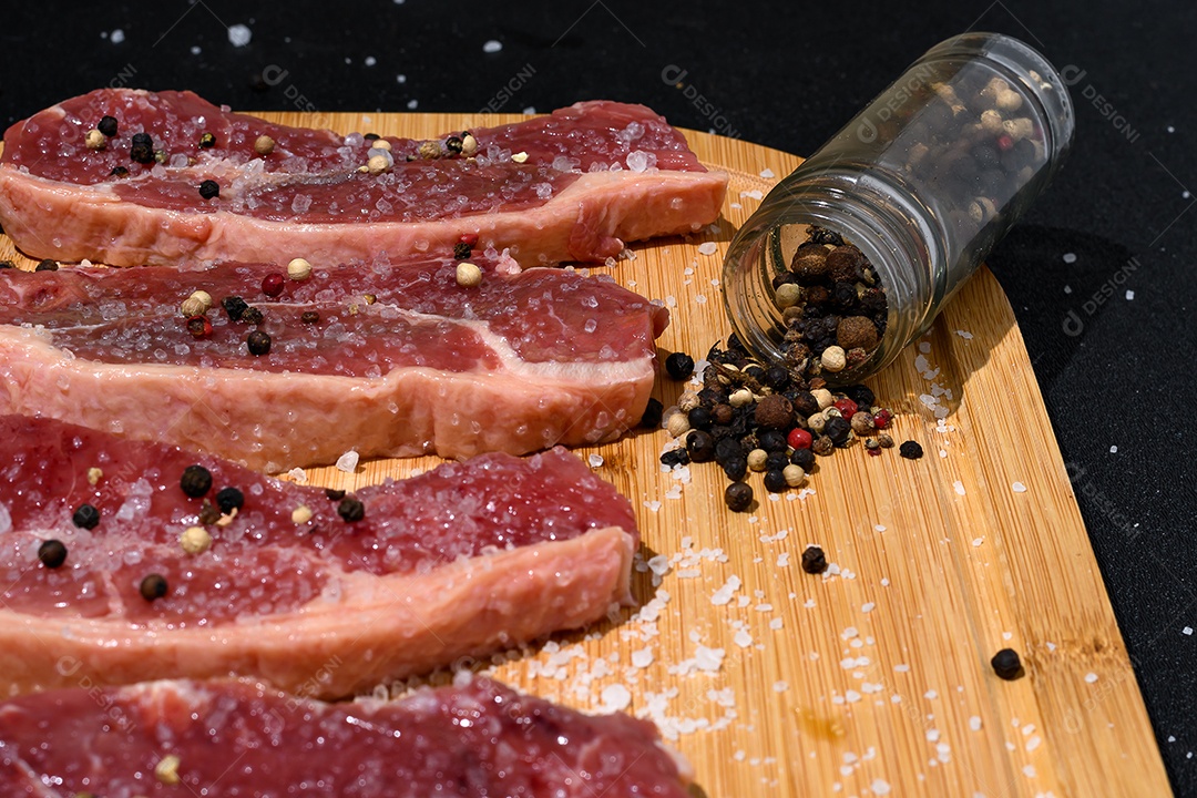 Carnes cortadas temperadas sobre tábua de madeira para o churrasco