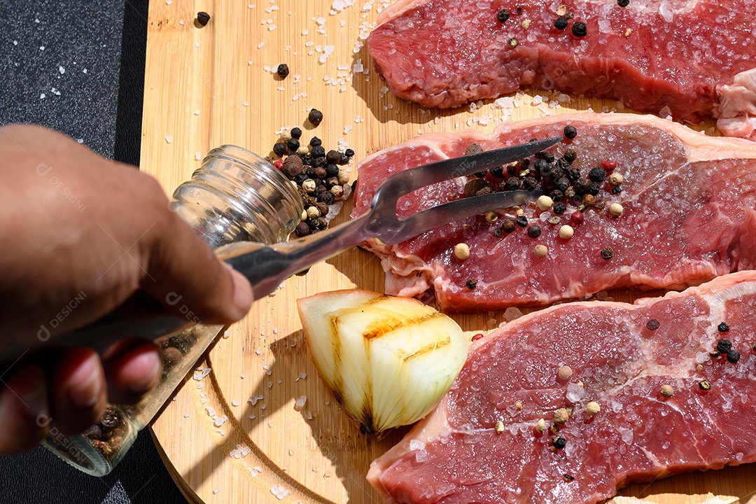 Carnes cortadas temperadas sobre tábua de madeira