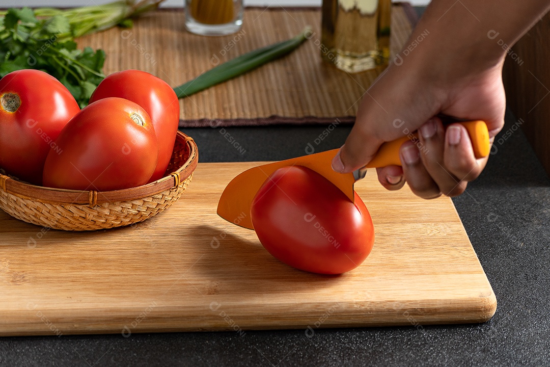 Mão cortando tomates para temperar comida