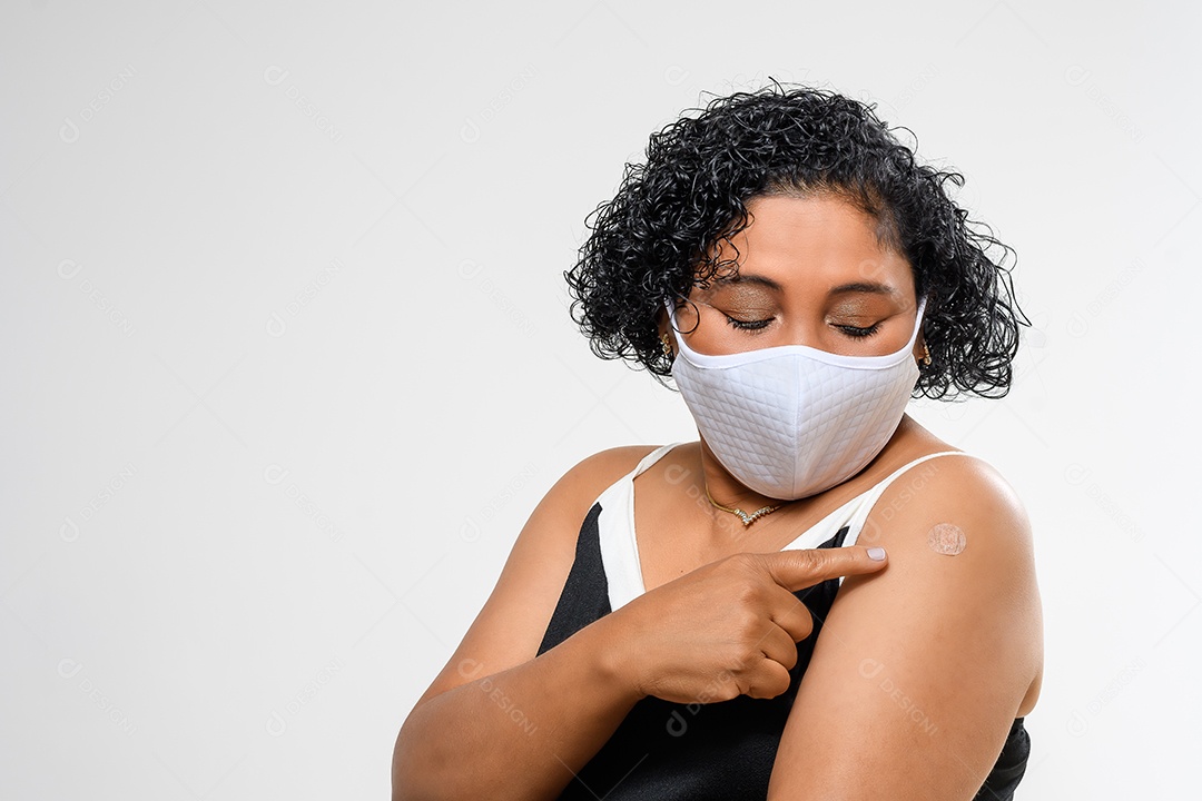 Mulher usando máscara e mostrando sinal de vacinação