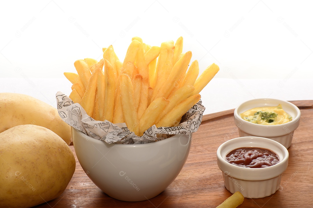 Batatas fritas em uma tigela com molhos ao lado