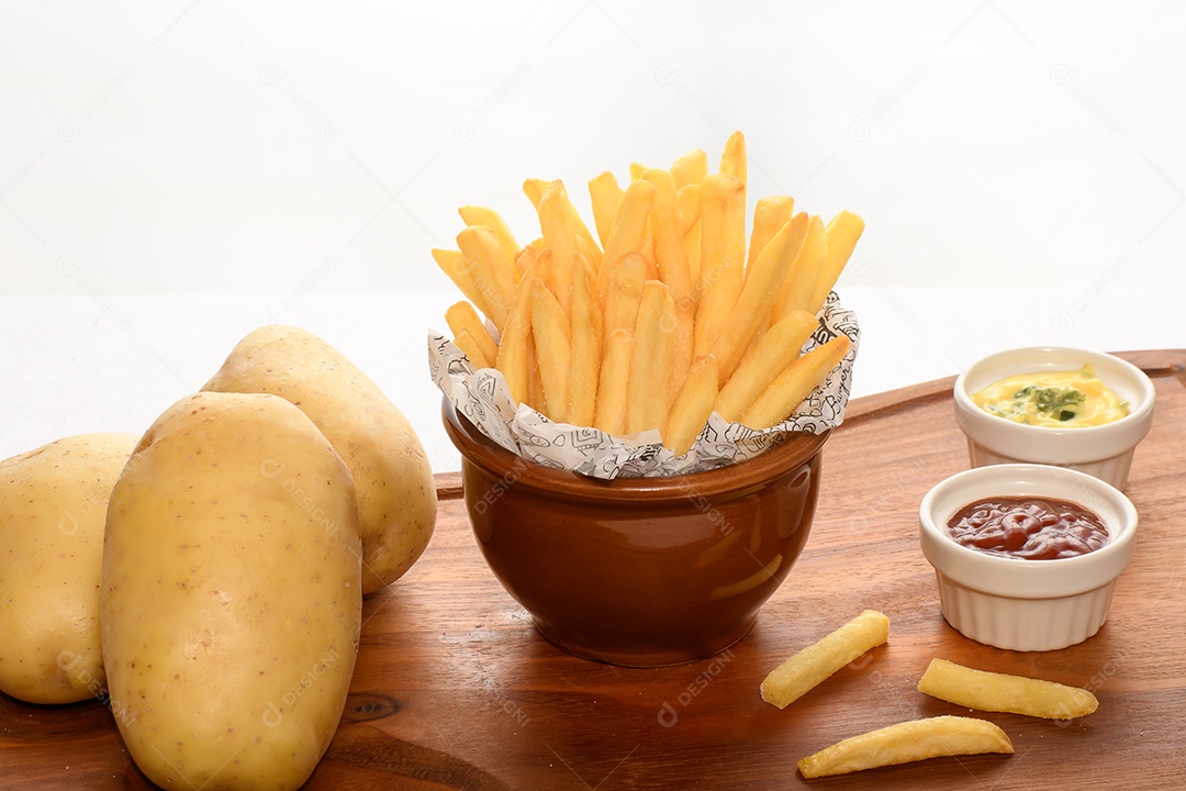 Tigela com batatas fritas e molhos ao lado