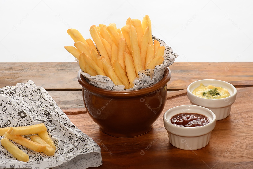 Tigela com batatas fritas e molhos ao lado