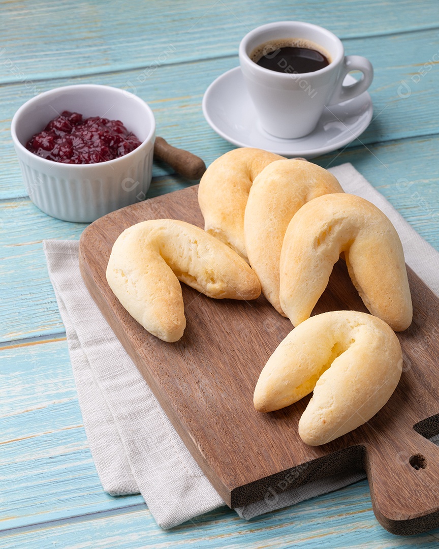 Tábua com chipas e geleia e uma xícara de café