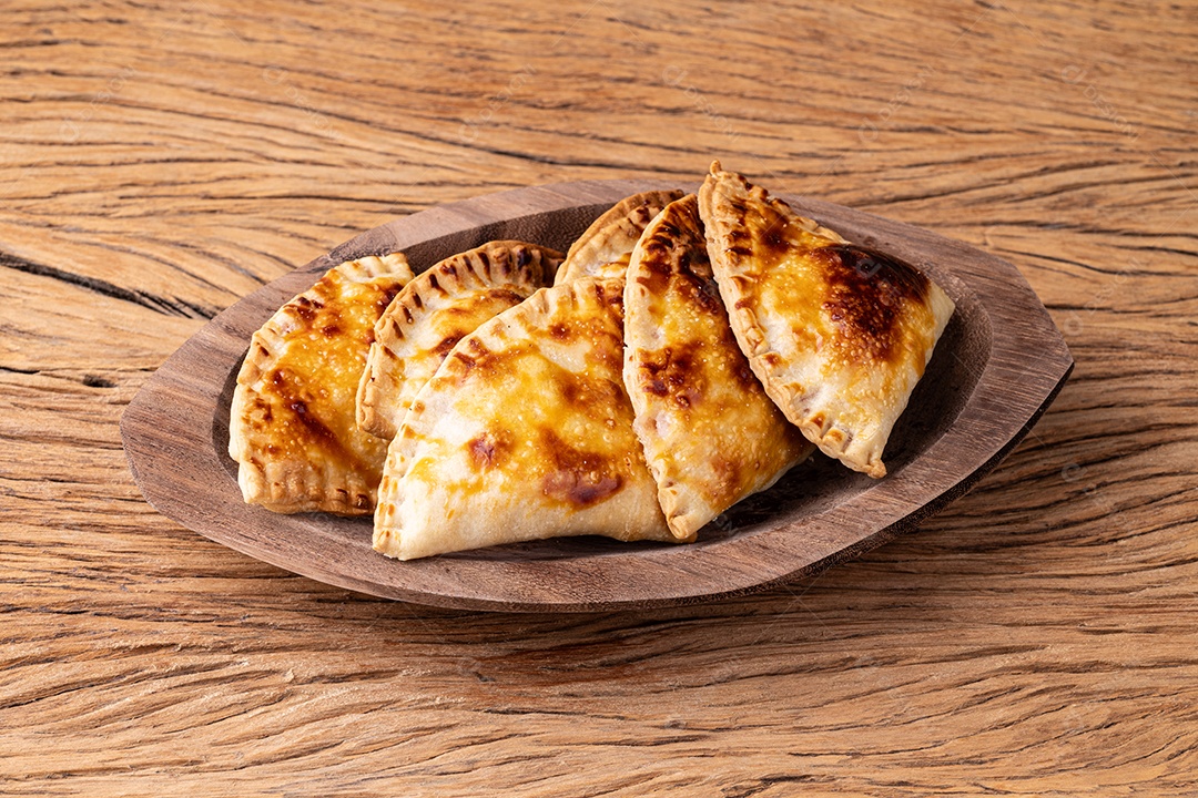 Lanche típico brasileiro assado pastel em um prato sobre a mesa de madeira