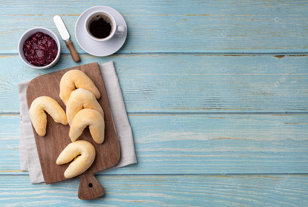 Tábua de madeira com chipas de queijo geleia e café