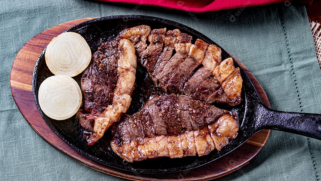 Picanha fatiada com cebola sobre frigideira