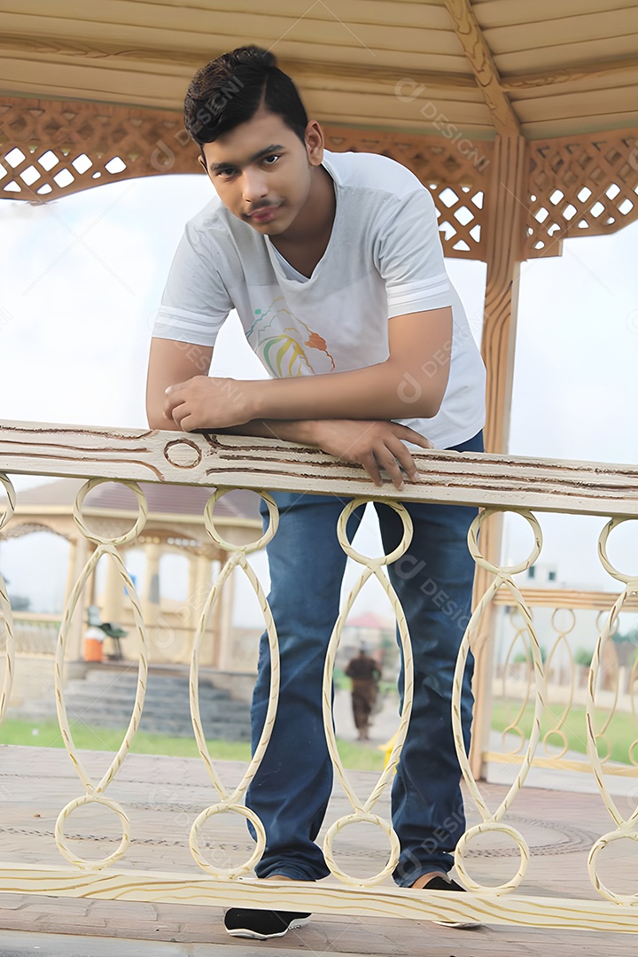 Jovem indiano encostado na grade de um banco do parque