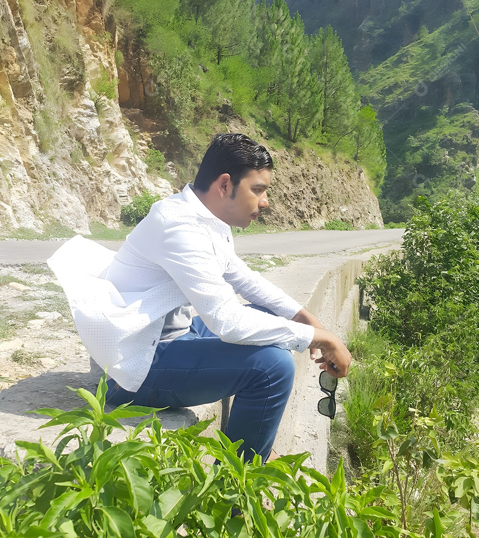 Jovem sentado em uma estrada de montanha