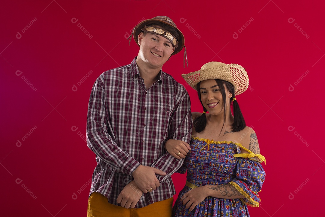 Casal de braços dados e trajados para festa junina