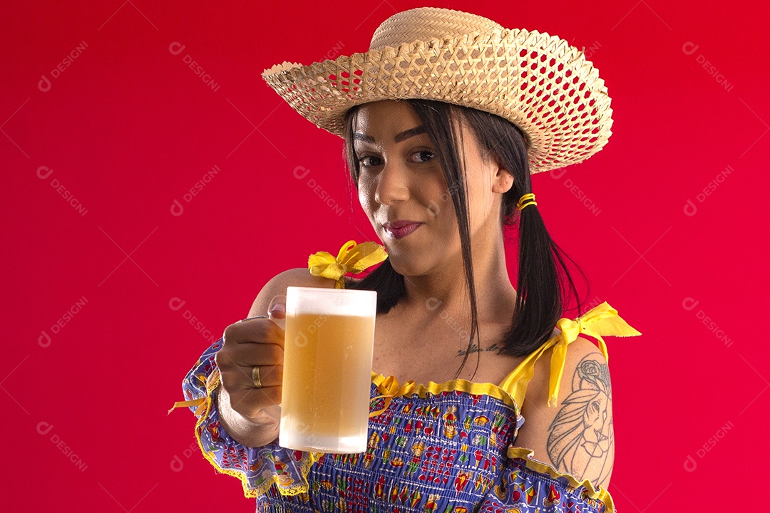 Jovem bonita com trajes juninos e segurando caneca de cerveja