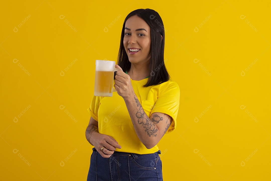 Jovem com caneca de cerveja na mão comemorando jogo do Brasil