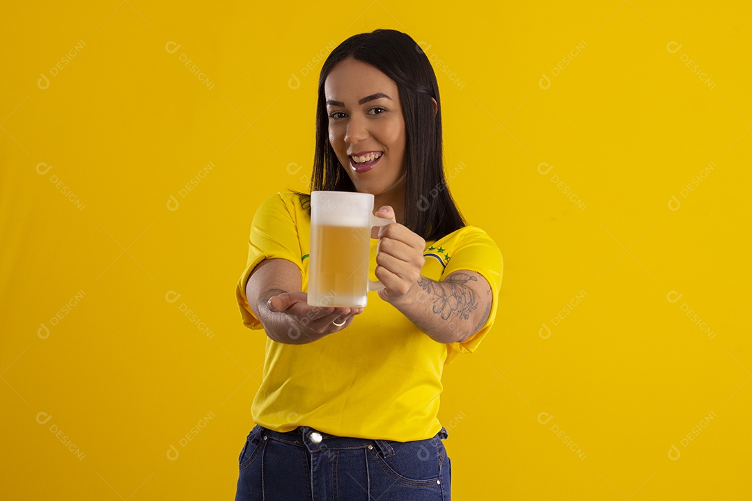 Jovem com caneca de cerveja na mão comemorando jogo do Brasil