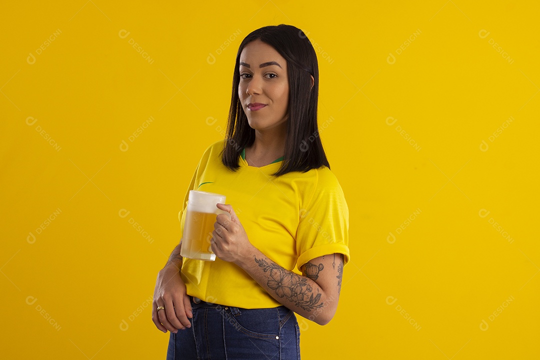 Jovem com caneca de cerveja na mão comemorando jogo do Brasil