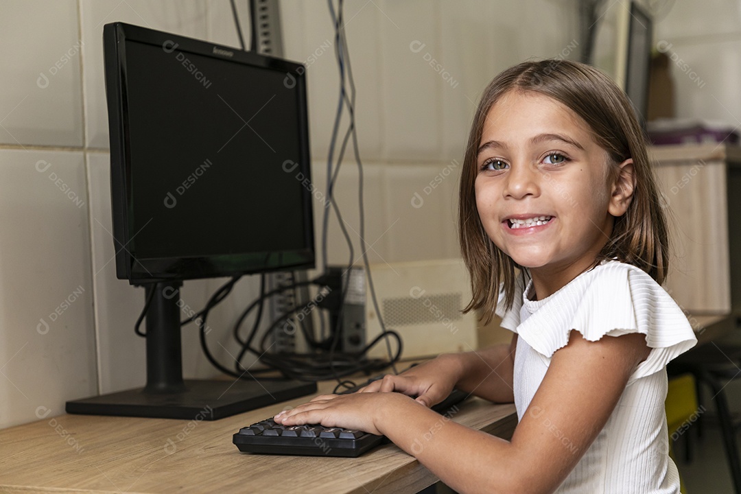 Garotinha sorridente com mãos nas teclas de um computador