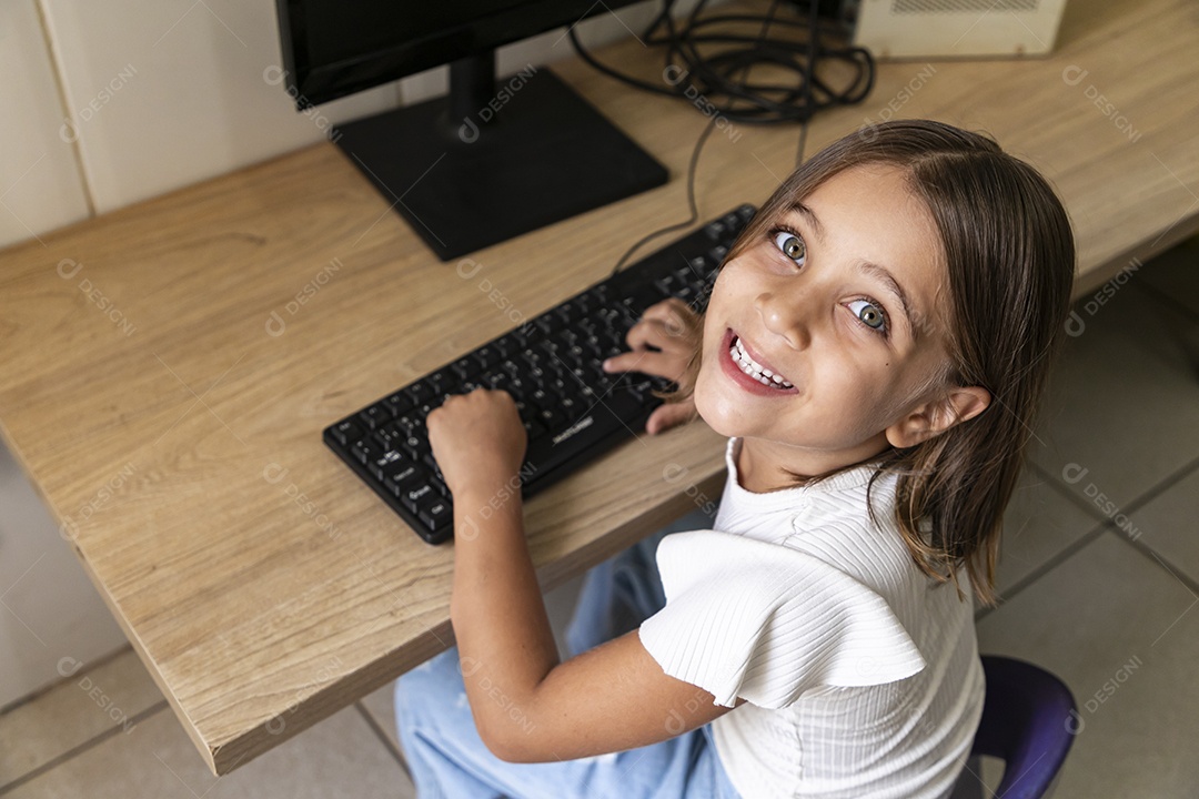 Linda garotinha feliz com mãos no teclado