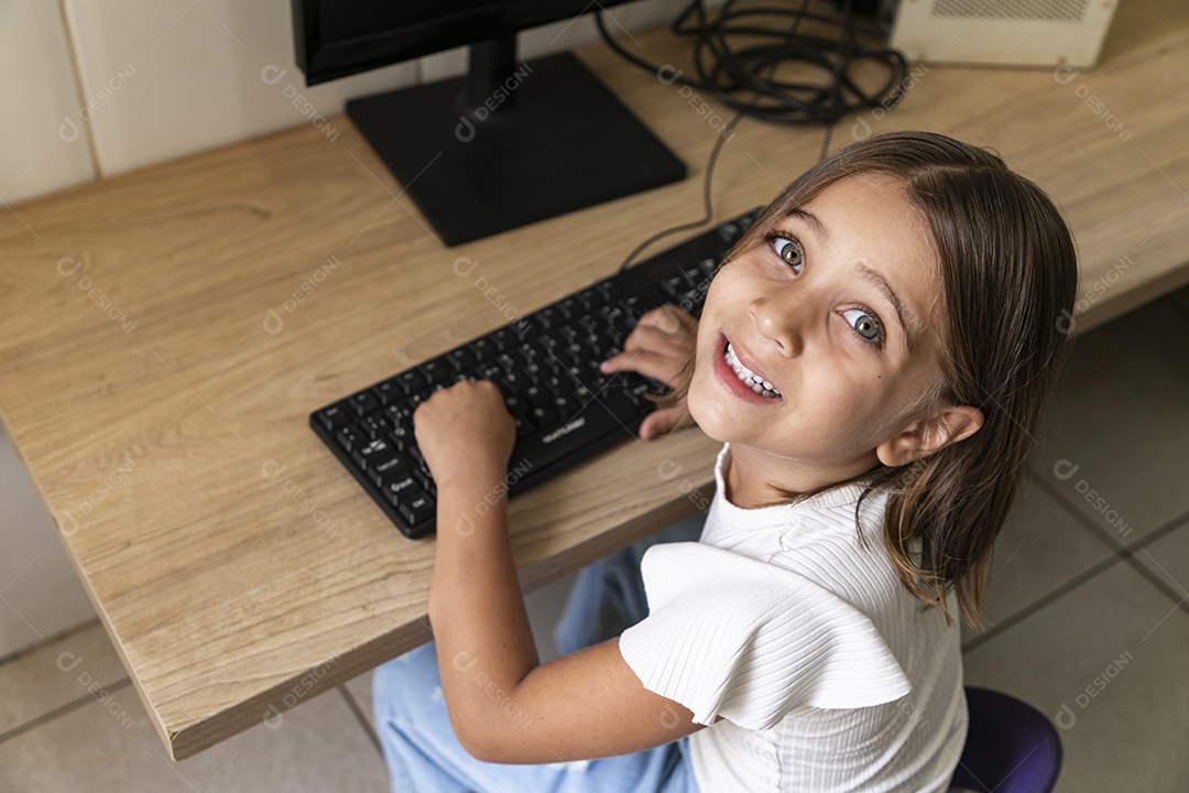 Linda garotinha com mãos no teclado de um computador