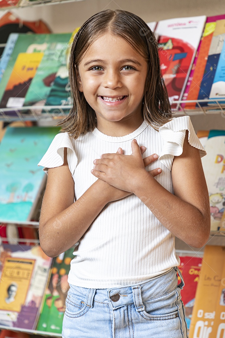Garota linda com mãos no peito em uma livraria
