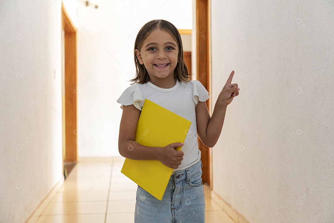 Menininha com caderno nas mãos apontando para cima