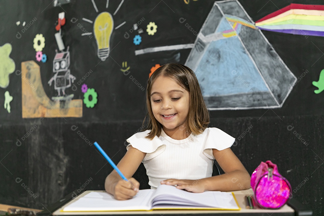Garotinha escrevendo em uma caderno na sala de aula