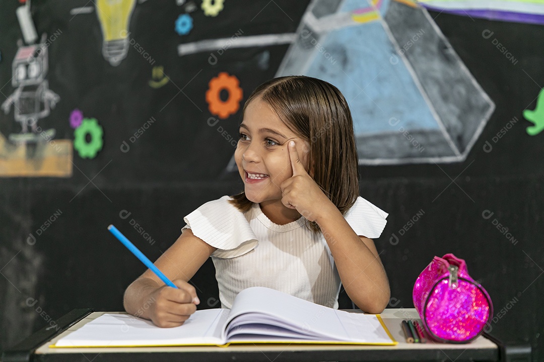 Garotinha feliz escrevendo em um caderno estudando