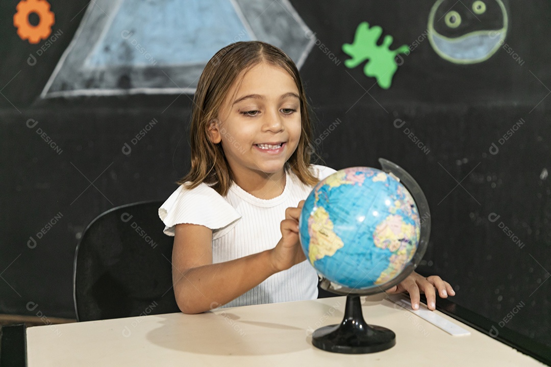 Linda menininha concentrada olhando um globo terrestre