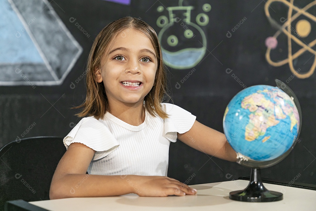 Menina fofa e alegre com mão em um globo terrestre