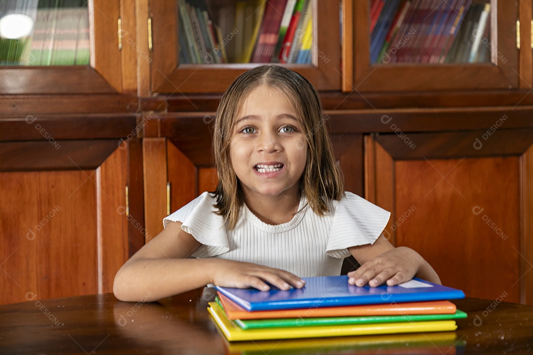 Garotinha feliz em uma biblioteca cheia de cadernos