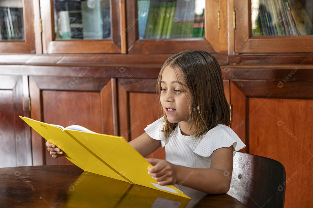 Garotinha lendo um livro concentrada