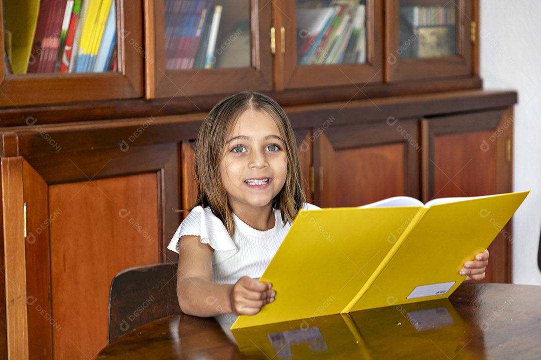 Beautiful little girl reading a book in a library