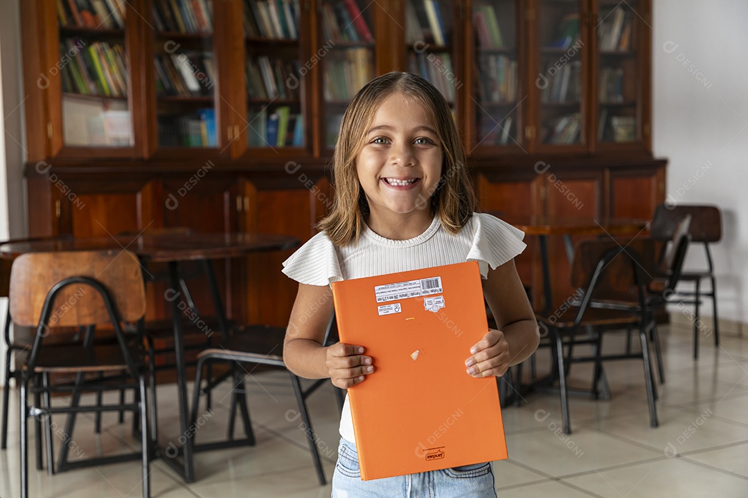 Linda menina segurando caderno em uma livraria