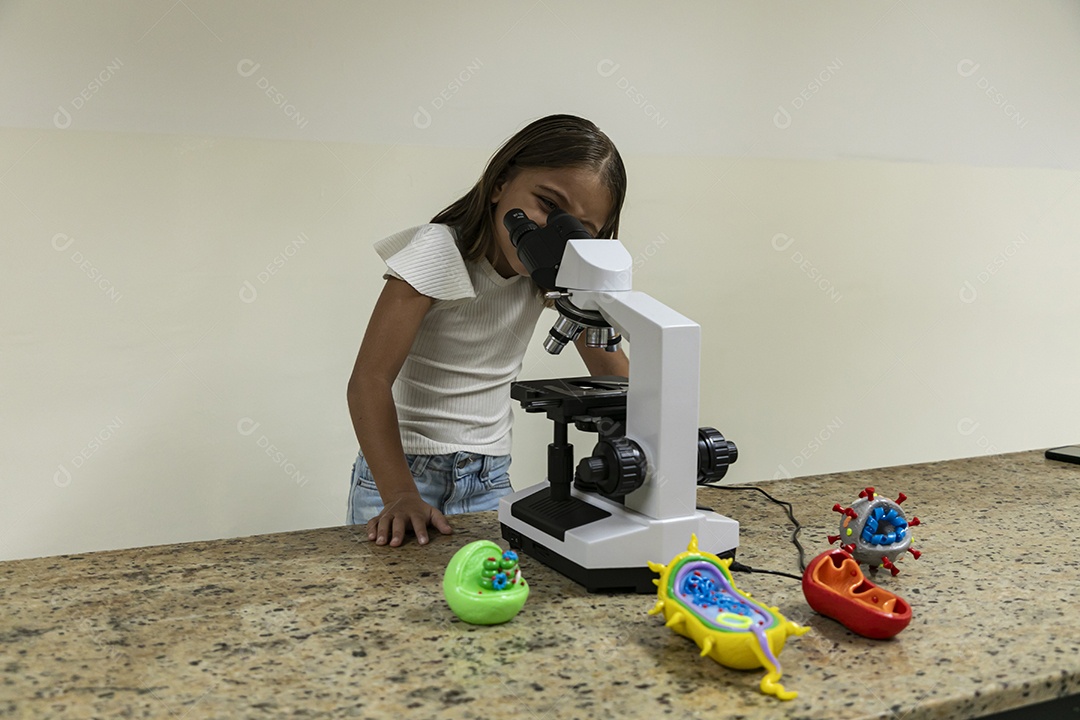 Garota olhando através de um microscópio