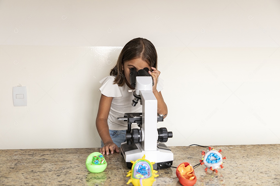 Menina fofa olhando através de um microscópio