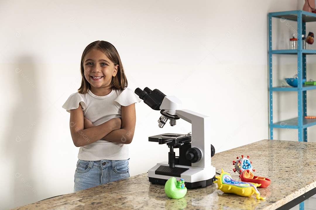 Menina fofa de braços cruzados na frente de um microscópio